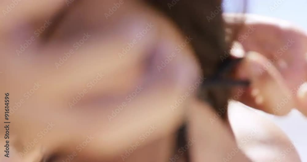 Close up crop of beautiful young woman tying bikini on beach rear view