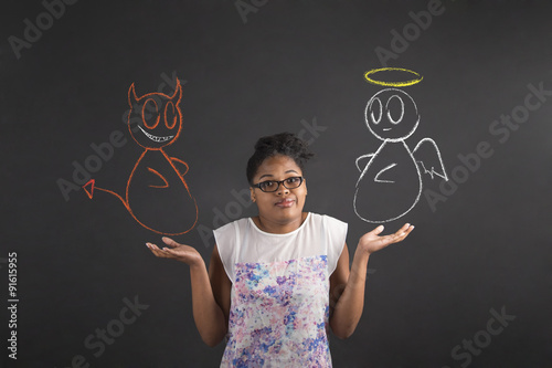 African woman with an I don't know angel and devil gesture on blackboard background