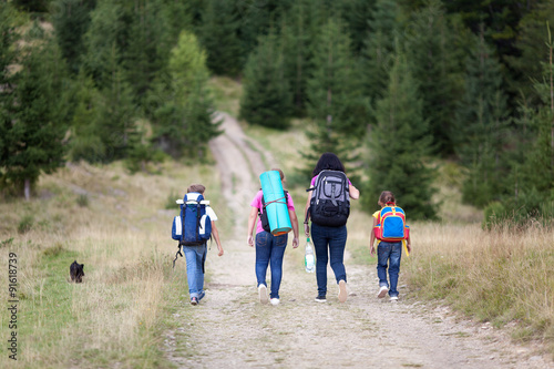 Family walk with backpacks from back