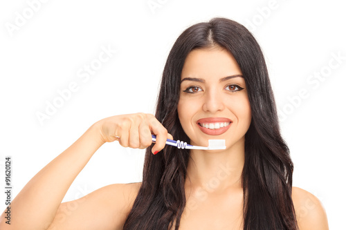 Beautiful young woman brushing her teeth