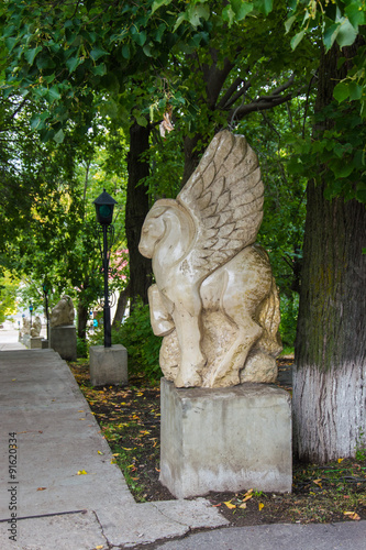 каменная скульптура лошади с крыльями в городском парке