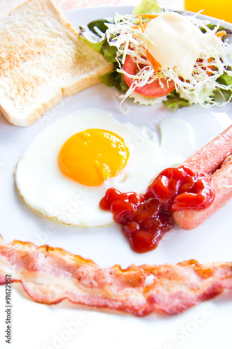 fried eggs with bacon  sausages and toasts on white plate