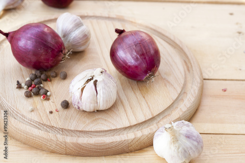 Red onion and garlic bulbs on wooden board close-up  selective focus