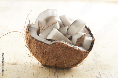Quadro su tela half coconut filled with coconut chunks on a wooden plank
