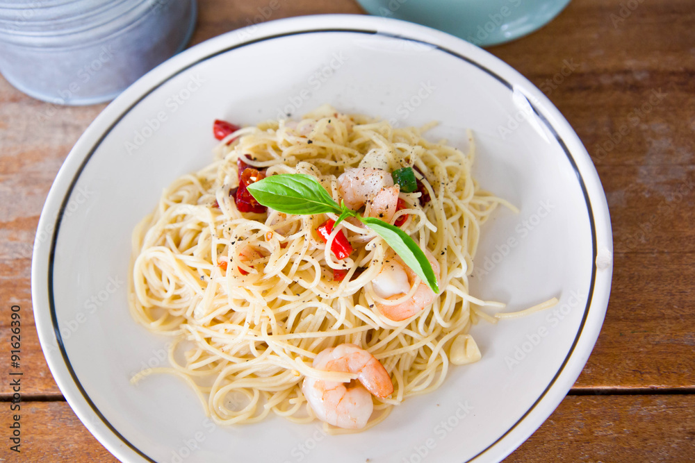 Chilli prawn spaghetti on wooden table in restaurant