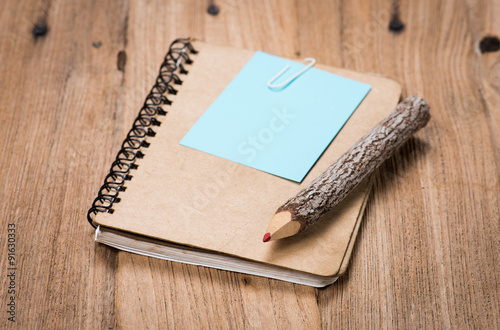 brown notebook and a pencil on wood background
