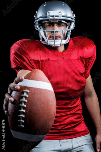 Portrait of determined American football player showing ball