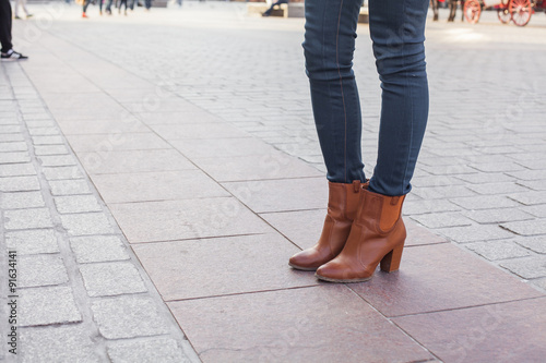 Slim model legs in blue jeans. Autumn fashion creation. On the background oldtown.