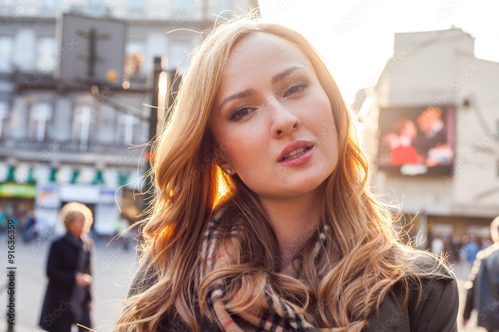 Beautiful blonde happy woman walking on the street in city. Outdoor photo. Beautiful blonde happy woman walking on the street in city. Outdoor photo.