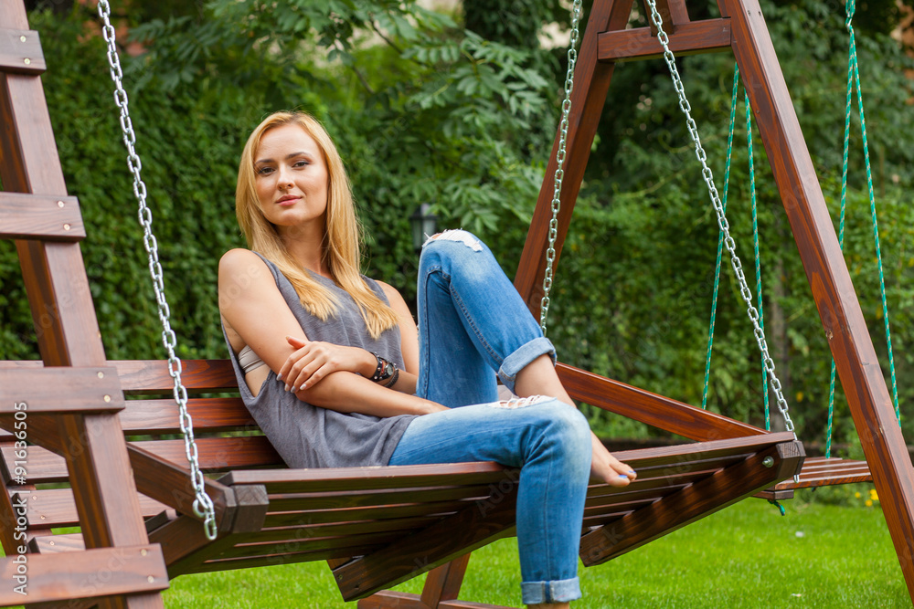 Sensual blonde woman sitting in park on wooden bench. Outdoor ph Sensual blonde woman sitting in park on wooden bench. Outdoor ph