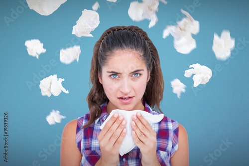 Composite image of portrait of sick woman sneezing in a tissue