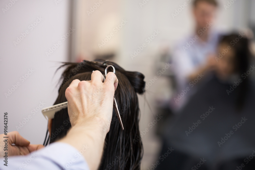 Fototapeta premium A hairdresser making a haircut for a brunette girl