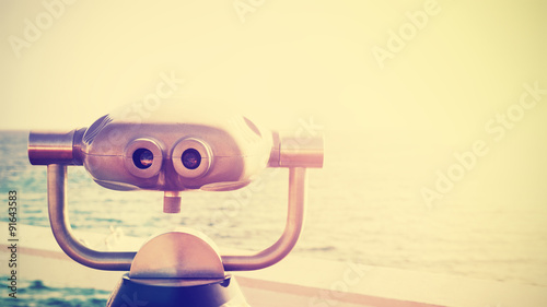 Vintage toned photo of a binocular pointed at horizon, California, USA.