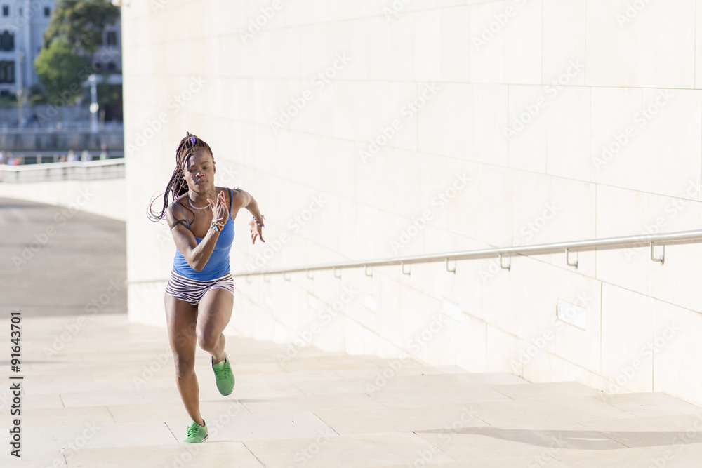 Beautiful sporty african woman running on stairs, health concept.