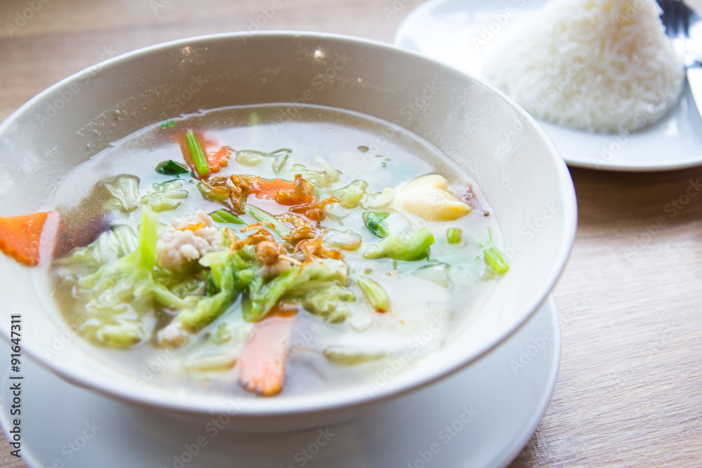 Traditional pork soup served in a white bowl over vegetable back