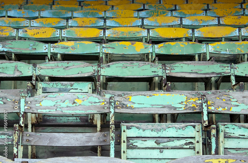 Old painted wooden seats of a stadium grandstand.