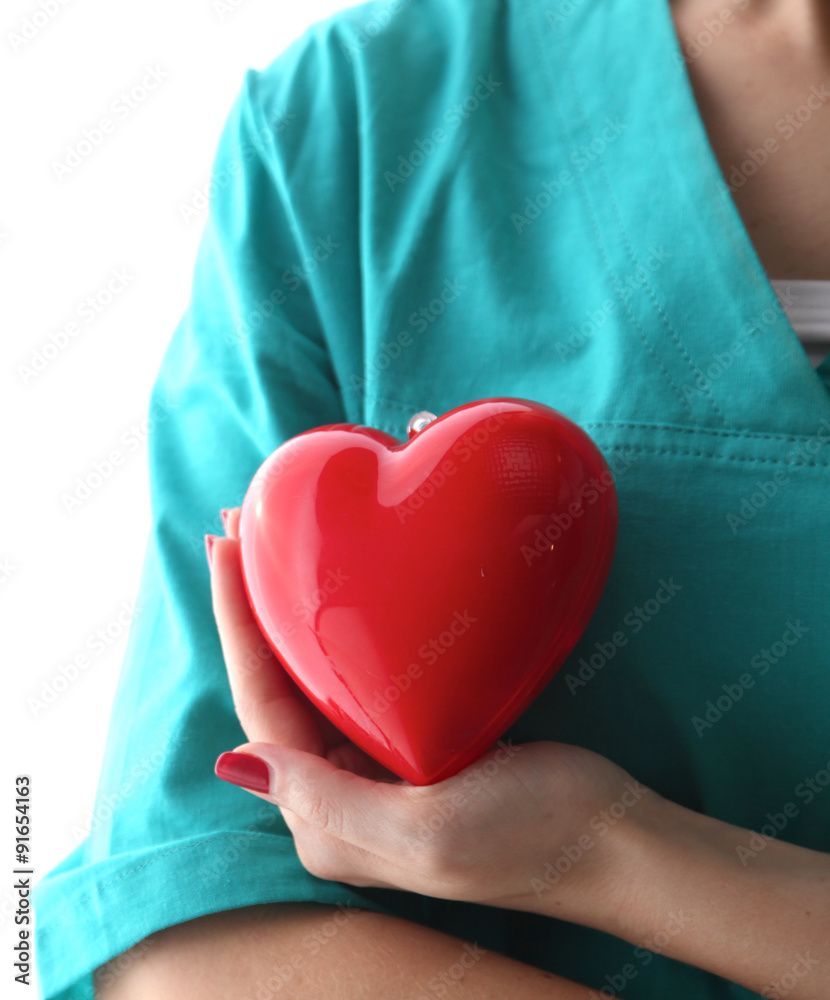 Young woman doctor holding a red heart, in office - obrazy, fototapety, plakaty 