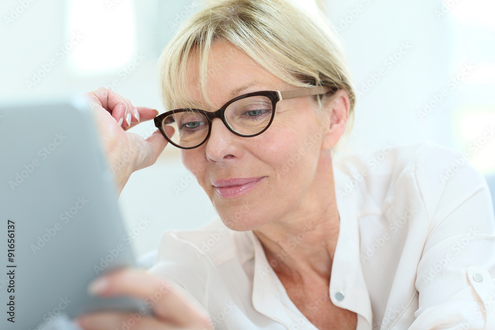 Senior woman with eyeglasses connected on digital tablet