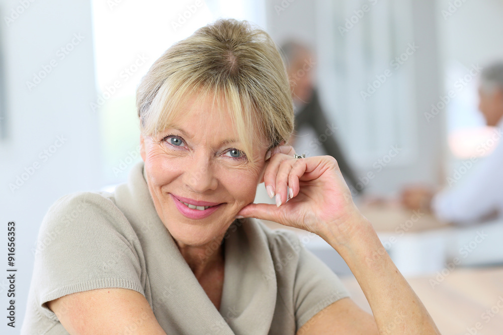 Portrait of smiling senior woman, people in background Portrait of smiling senior woman, people in background