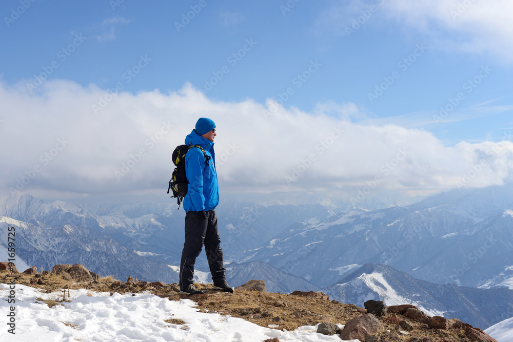 Hiker with backpack is standing in the winter mountains and look Hiker with backpack is standing in the winter mountains and look