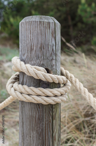 Thick rope bound to weathered wooden pole © tomeyk