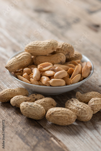 Peanut or arachis in white bowl on wood table.