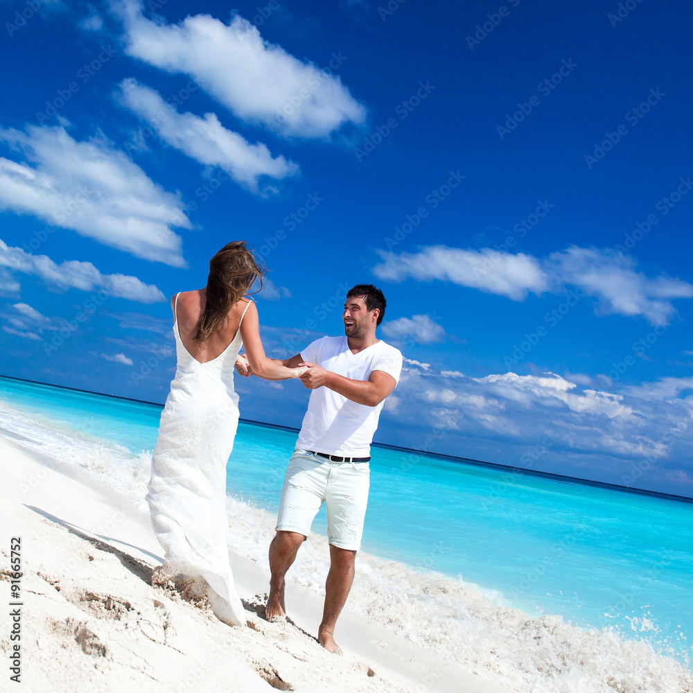 Happy newlyweds having fun on beach