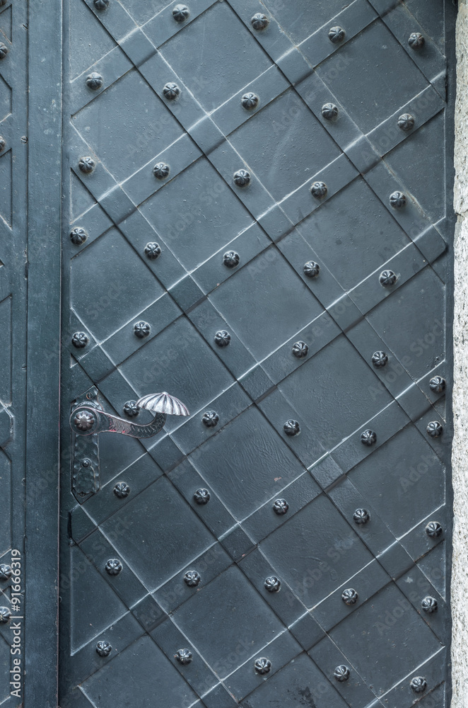 old iron door with handle, reinforced with steel belts and rivets old iron door with handle, reinforced with steel belts and rivets