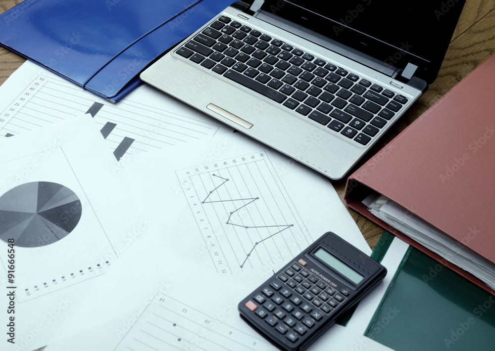 Modern business workplace with laptop and some papers with chart Modern business workplace with laptop and some papers with chart