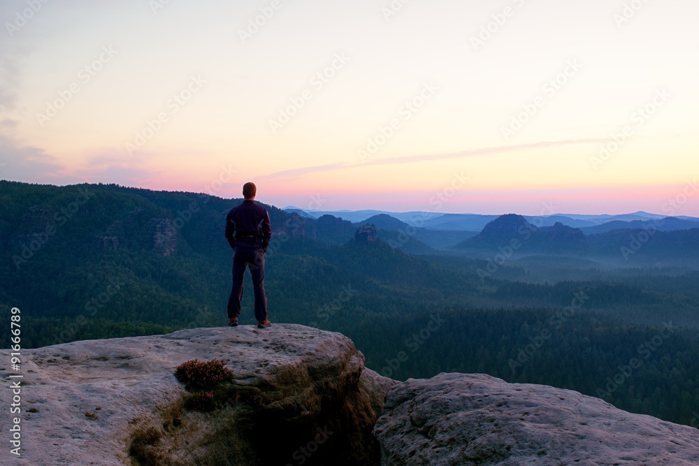 Hiker stand on the cliff of sandstone rock empire and watch over the misty and foggy morning valley