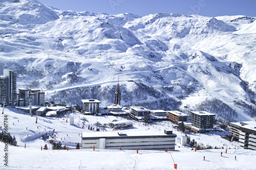 Winter Snowy High mountain panorama of French ski resort of Les Menuires in 3 Valleys with the ski lifts, chalets in the centre of the village and ski slopes in the background