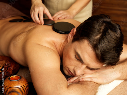 man having stone massage in spa salon