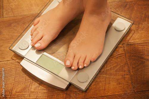 Woman's feet standing on weight scale.