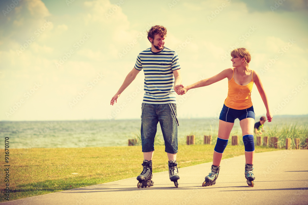 Young couple on roller skates riding outdoors Young couple on roller skates riding outdoors