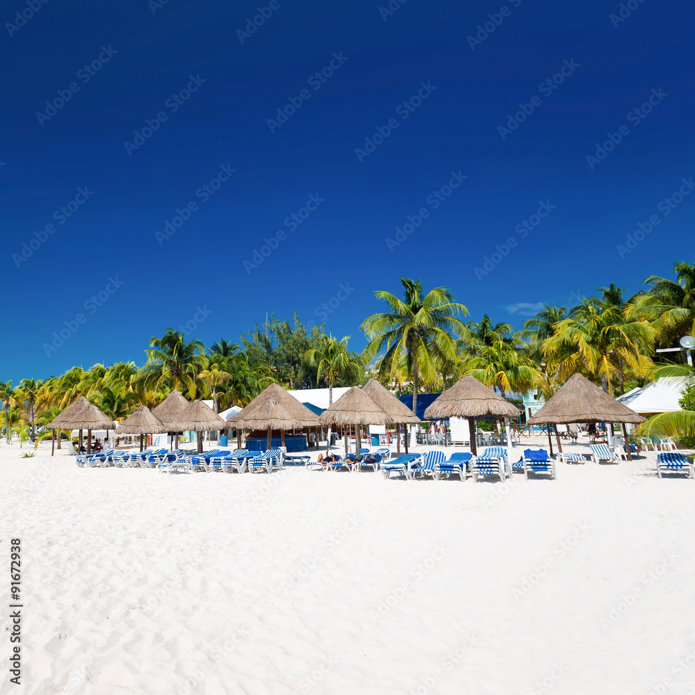 Caribbean beach with sun umbrellas and beds