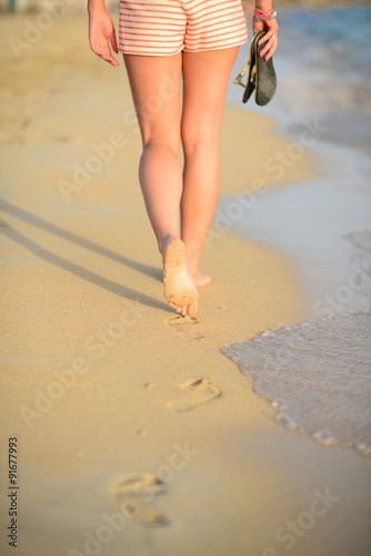 Beach travel - woman walking on sand beach leaving footprints in
