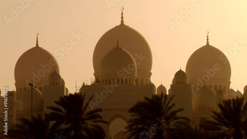 The domes of the beautiful Sheikh Zayed Mosque in Abu Dhabi, United Arab Emirates at sunset.