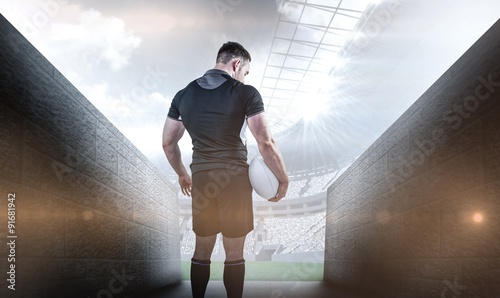 Composite image of tough rugby player holding ball
