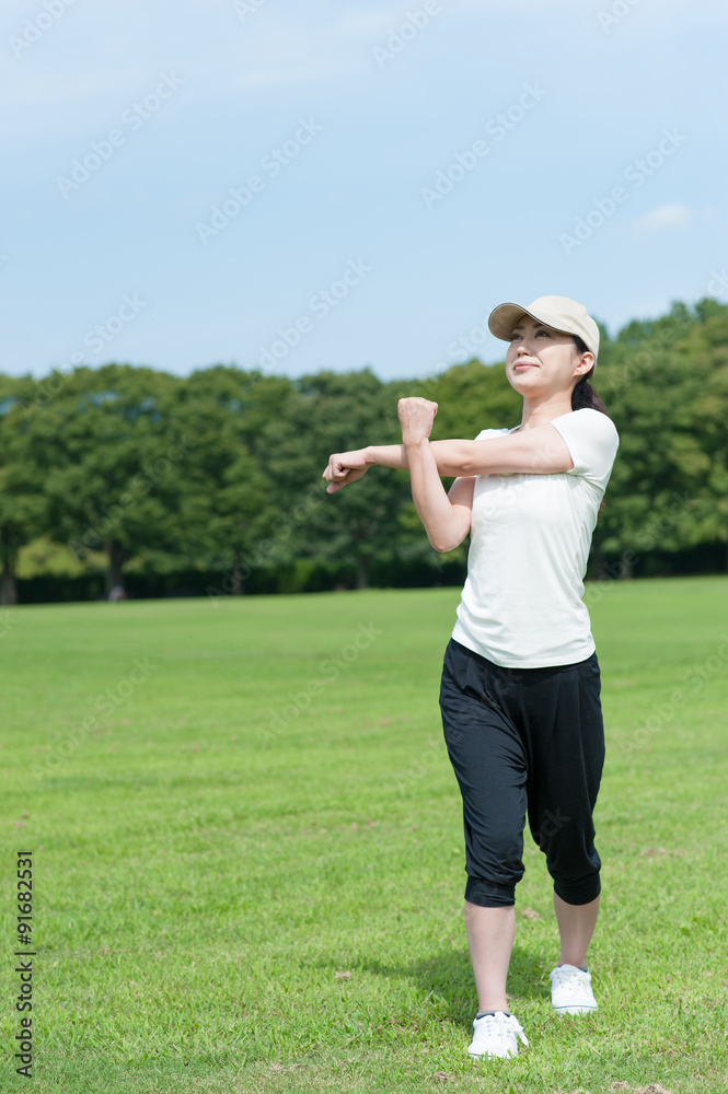 芝生の上でストレッチをする日本人女性