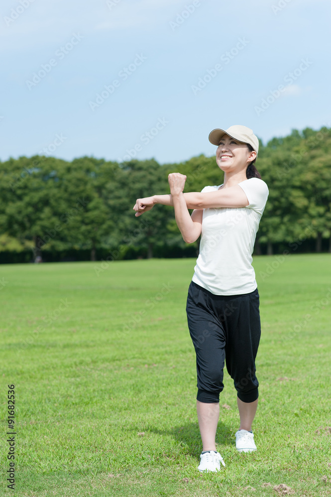 芝生の上でストレッチをする日本人女性