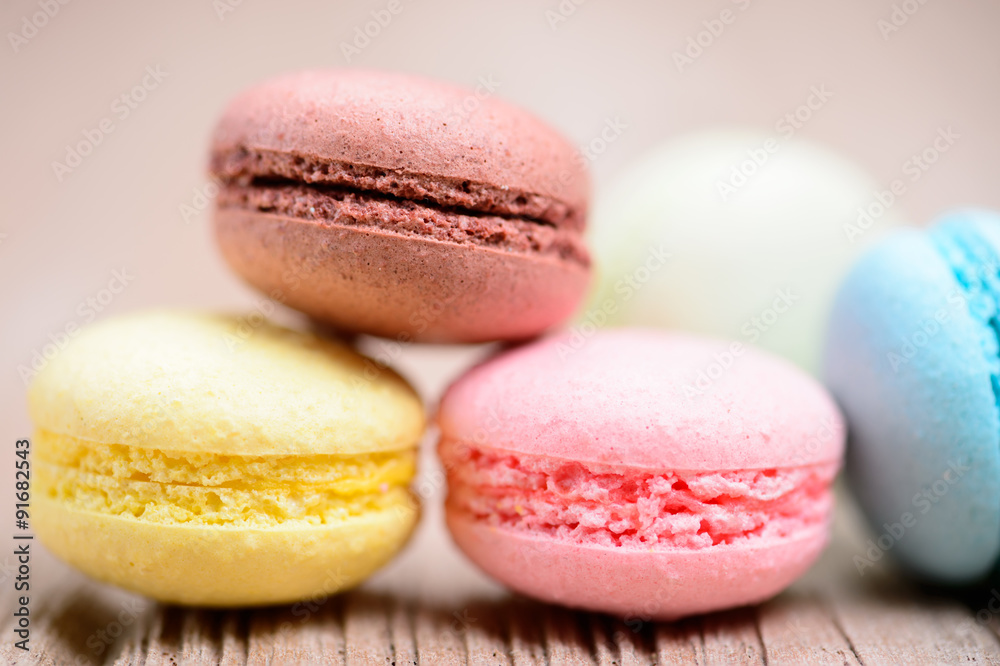 A lot of french colorful macarons on a woody floor A lot of french colorful macarons on a woody floor
