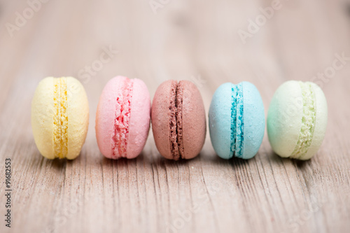 A lot of french colorful macarons on a woody floor