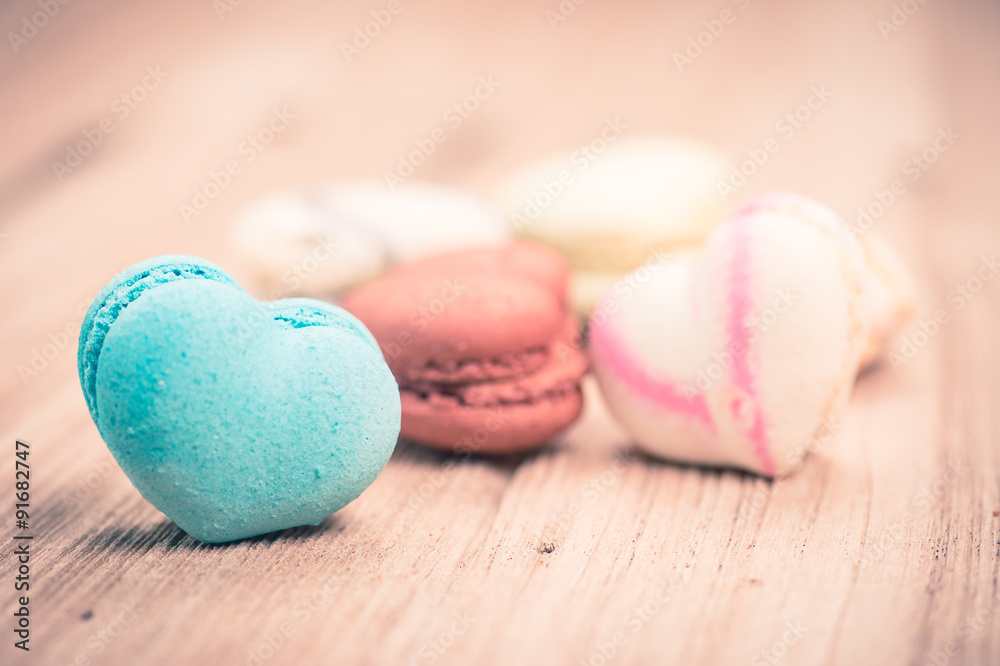 A lot of french colorful macarons in .heart shape on a woody flo A lot of french colorful macarons in .heart shape on a woody flo