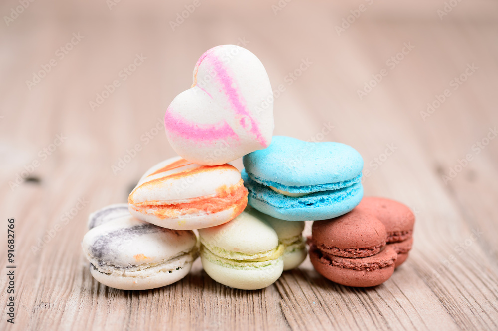 A lot of french colorful macarons in .heart shape on a woody flo A lot of french colorful macarons in .heart shape on a woody flo
