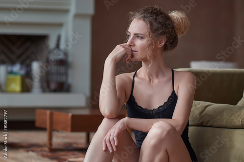 Portrait of young sad woman sitting on the floor at home