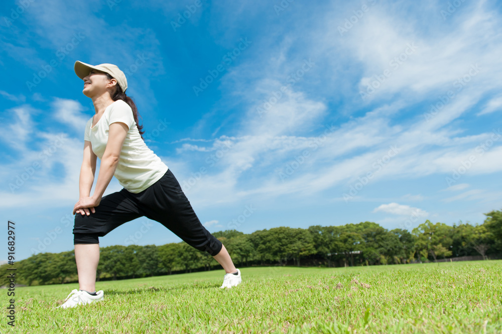 芝生の上でストレッチをする日本人女性