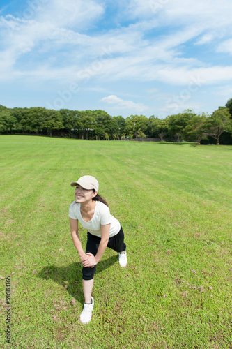芝生の上でアキレス腱をストレッチしている女性