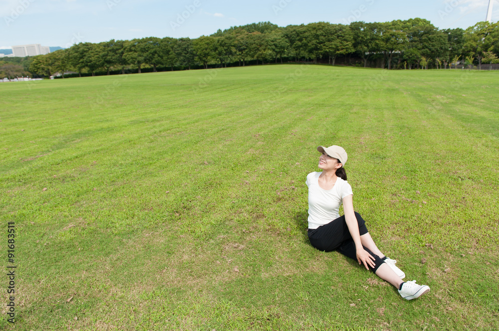 芝生の上でストレッチをする日本人女性