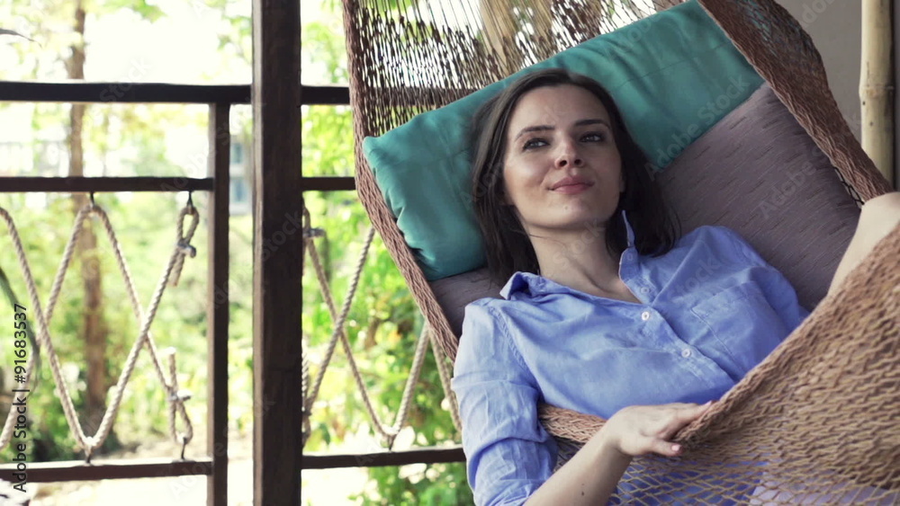 Happy woman relaxing on hammock on terrace 
