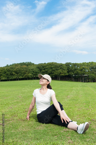 芝生の上でストレッチをする日本人女性